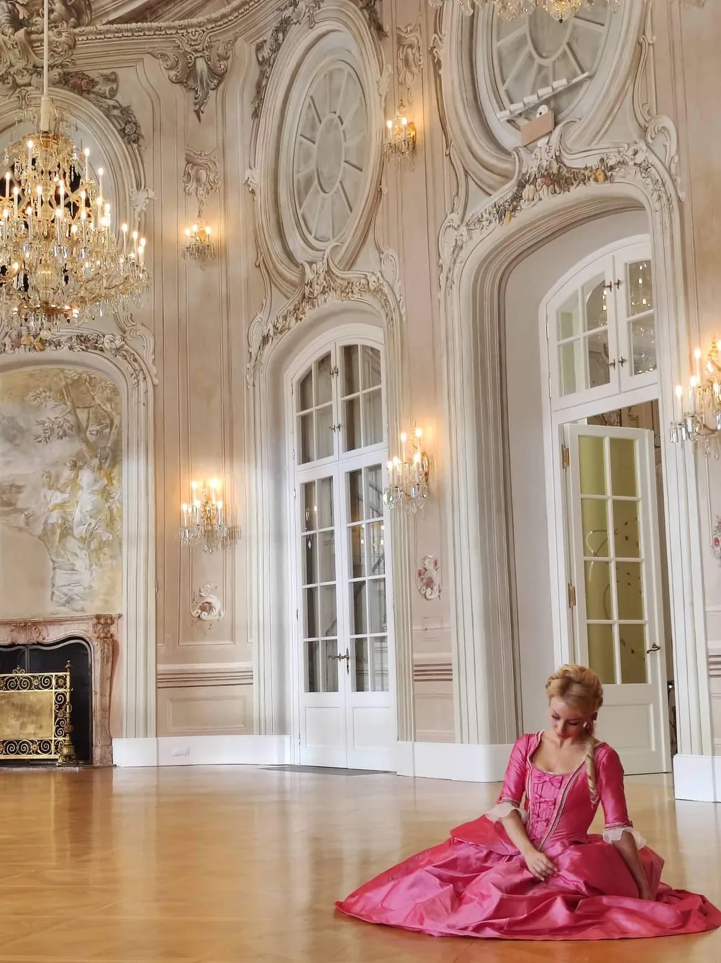 Aleksandra Liashenko seated in a rococo ballroom